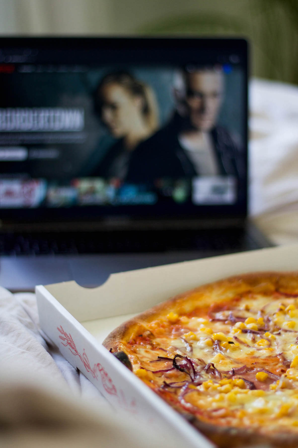 Pizza und Netflix am Laptop im Bett 
