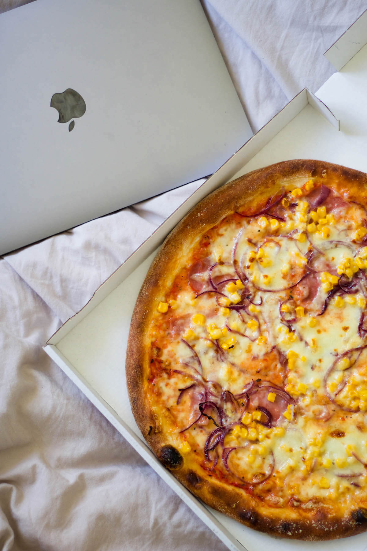 Bestellte Pizza und Laptop im Bett 